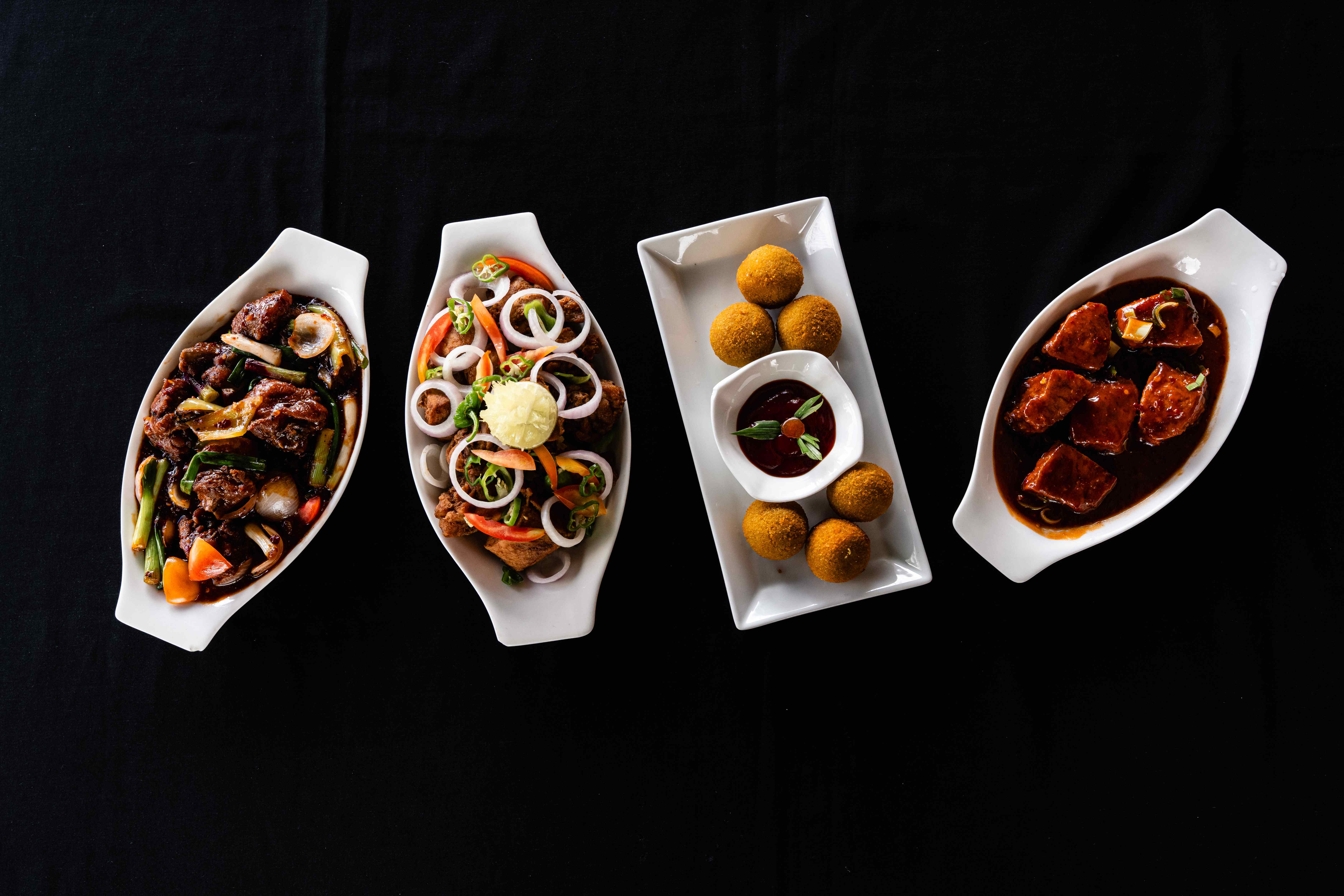 Four Chopsticks dishes arranged for sharing on a black table
